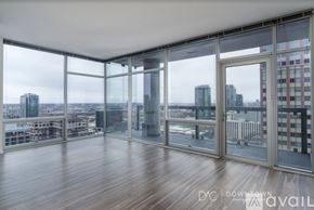 Chicago apartment for rent - A spacious room with wooden floors and large windows overlooking a cityscape.
