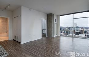 Chicago apartment for rent - A spacious room with wooden floors and a view of the city through large windows.