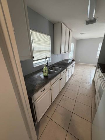 Orlando apartment for rent - A kitchen with white cabinets and a black countertop.