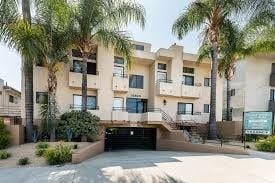 Tarzana apartment for rent - A building with a black gate in front of it surrounded by palm trees.