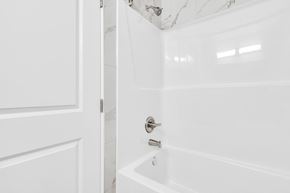 Edmonton apartment for rent - A white bathroom with a tub and a door.