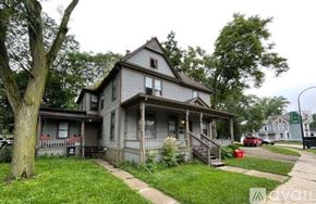 Ypsilanti apartment for rent - A house with a porch and a tree in front of it.