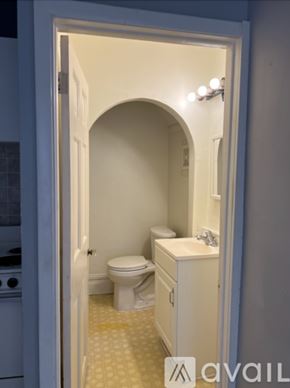 Ypsilanti apartment for rent - A bed with a floral comforter sits in a room with a lamp and a window.