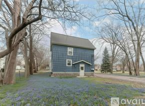 Ypsilanti apartment for rent - A blue house surrounded by trees and a car parked in front.