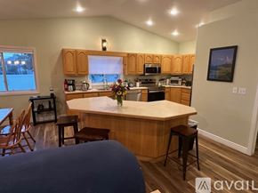 Weiser house for rent - A kitchen with wooden cabinets and a large island with a vase of flowers on it.