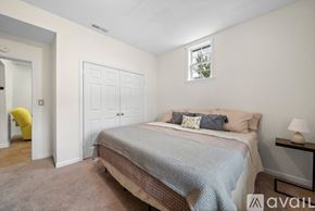 Winston-Salem apartment for rent - A bedroom with a bed, a yellow chair, and a nightstand with a lamp.