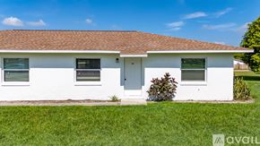 Kissimmee townhouse for rent - A white house with a brown roof and a green lawn in front.