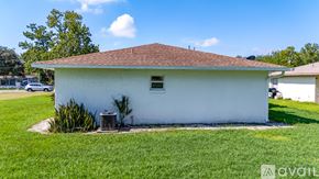 Kissimmee townhouse for rent - A small white building with a brown roof is surrounded by a grassy area.