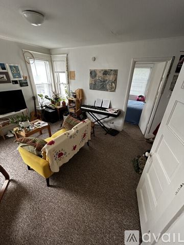 Ypsilanti apartment for rent - A living room with a yellow couch and a white door.