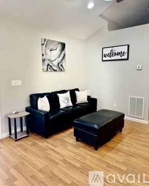 Marion house for rent - A black couch with a white pillow and a black ottoman in a room with wooden flooring.