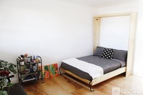 Denver apartment for rent - A bedroom with a bed, a cart, and a plant.