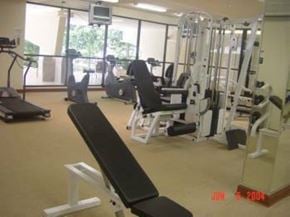 Honolulu condo for rent - A gym with a variety of equipment including weights and a treadmill.
