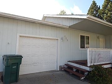 Post Falls house for rent - A white house with a green trash can in front of it.