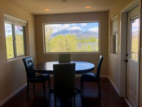 Flagstaff house for rent - A dining room with a table and chairs and a view of the mountains outside.