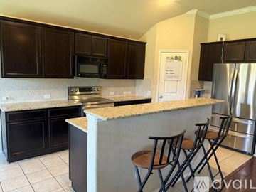 Frisco house for rent - A kitchen with black cabinets and a granite countertop.