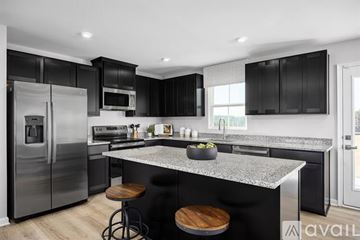 Wellford house for rent - A modern kitchen with black cabinets and a granite countertop.
