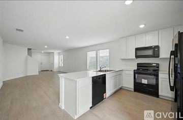 Little Elm house for rent - A kitchen with white cabinets and black appliances is available for rent.