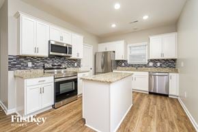 Jamestown house for rent - A kitchen with white cabinets and a granite countertop.