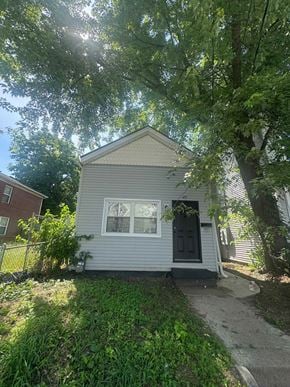 Louisville house for rent - A small house with a grey siding and a black door is surrounded by greenery.