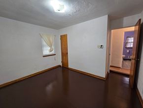 Gary house for rent - A room with a brown floor and a white wall with a window and a door.