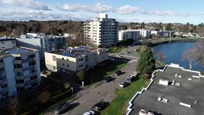 Victoria apartment for rent - A view of a residential area with apartment buildings, cars parked in a lot, and a body of water.