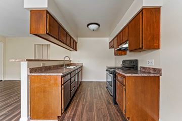 Burbank apartment for rent - A kitchen with wooden cabinets and a black stove top oven.