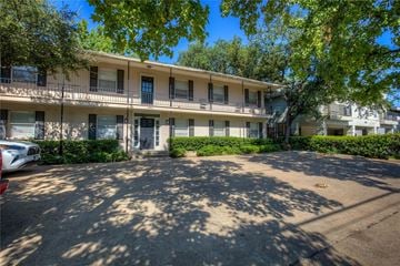 Dallas apartment for rent - A parking lot in front of a building with trees.
