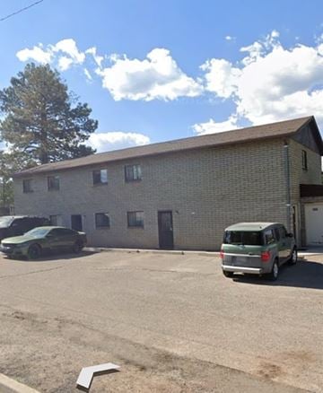 Flagstaff apartment for rent - A green van is parked in a lot in front of a brick building.