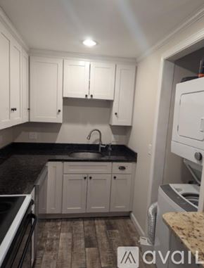 Portsmouth apartment for rent - A kitchen with white cabinets and a black countertop.