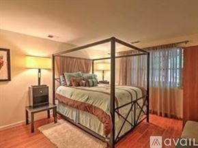 Atlanta apartment for rent - A bedroom with a four-poster bed and a small table with a lamp.