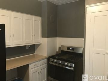 Warren house for rent - A kitchen with white cabinets and a black oven.