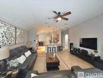 Fort Worth house for rent - A living room with a black couch and a ceiling fan.