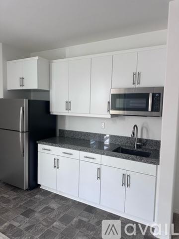 Menifee house for rent - A kitchen with white cabinets and a black fridge.