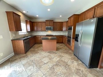 Clemmons house for rent - A kitchen with brown cabinets and a black refrigerator.