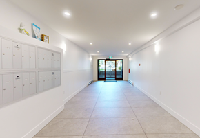Victoria apartment for rent - A long hallway with white walls and a row of lockers on the left side.