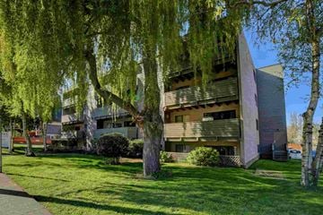 Victoria apartment for rent - A modern building with a triangular facade is surrounded by trees and grass.