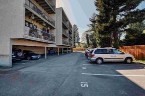 Victoria apartment for rent - A parking lot with cars parked and a building with balconies in the background.