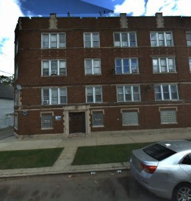 Chicago apartment for rent - A silver car is parked in front of a brick building.