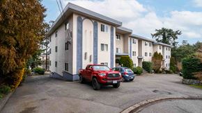 Victoria apartment for rent - A red car is parked in front of a white building with blue trim.