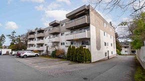 Victoria apartment for rent - A large concrete building with a parking lot in front.