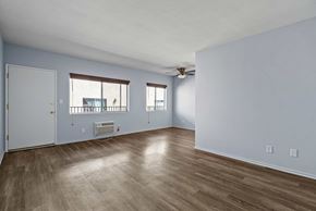 Burbank apartment for rent - A room with a white ceiling, a window with a view of a building, and a wooden floor.