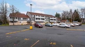 Brentwood Bay apartment for rent - A parking lot with cars and a building in the background.