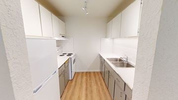 Brentwood Bay apartment for rent - A kitchen with white cabinets and a white fridge.