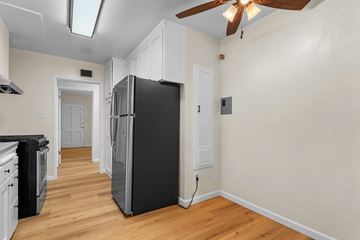 Burbank apartment for rent - A black refrigerator in a kitchen with wooden floors and white walls.