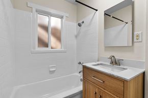 Burbank apartment for rent - A white tiled bathroom with a wooden vanity and a white bathtub.