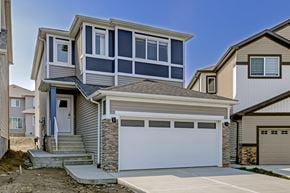 Edmonton apartment for rent - A modern house with a garage door and a stone pillar.