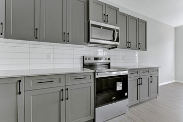 Edmonton apartment for rent - A kitchen with grey cabinets and a black oven.