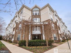 Aldie condo for rent - A large, two-story building with a beige and brown exterior and a large front porch.
