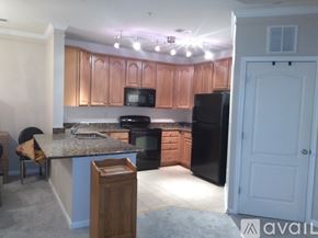 Aldie condo for rent - A kitchen with a black refrigerator and wooden cabinets.