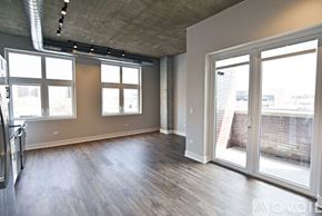Chicago apartment for rent - A spacious room with wooden floors and large windows.